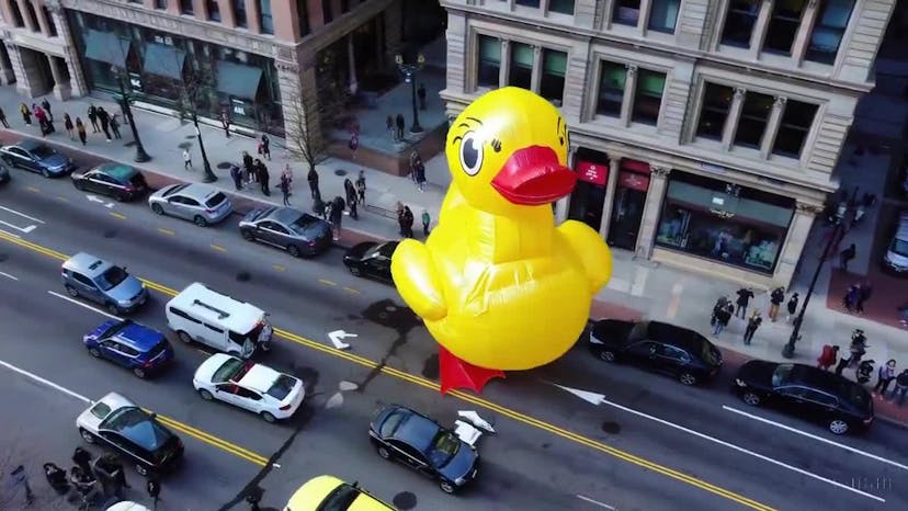 a giant duck walks through the streets in Boston